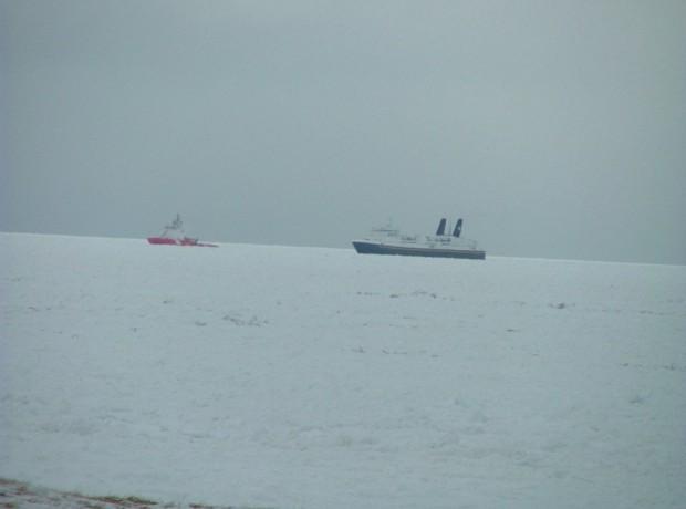 Image of the MV Caribou being guided through ice filled waters by the Canadian Coast Guard 